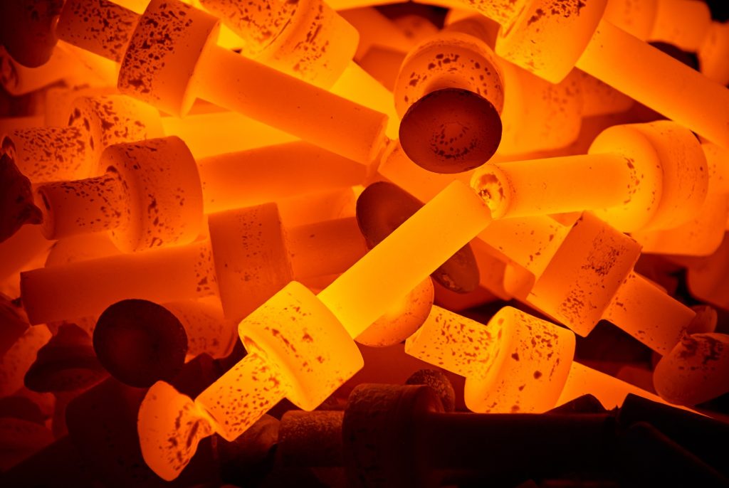 Rozżarzone metalowe elementy, mające barwę pomarańczowo-żółtą, podczas obróbki cieplnej w piecu