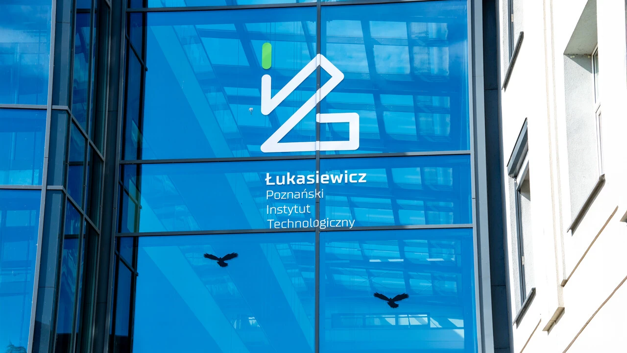 Logo Łukasiewicz - PIT na szklanym, frontowym wejściu do budynku przy ul. E. Estkowskiego w Poznaniu