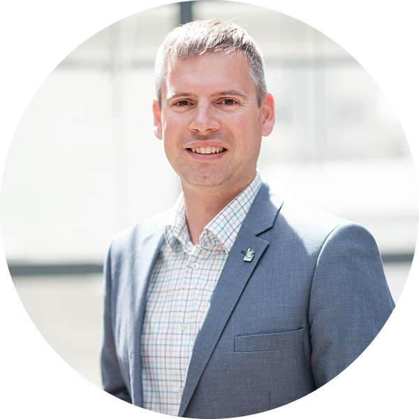 fotografia Piotra Nędzewicza, rozmyte tło, szary garnitur