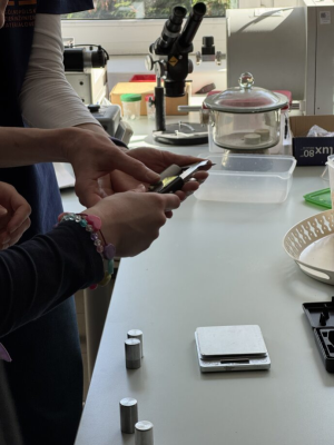 Ręce badaczki i ucznia, którzy mierzą materiały.