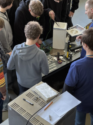 Grupa uczniów skupiona nad badaniem materiałów