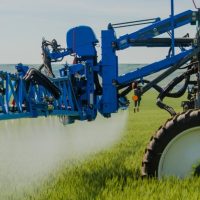Opryskiwacz rolniczy w kolorze niebieskim, nowoczesny sprzęt do ochrony roślin, podczas pracy na polu