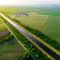 Rzeka płynąca przez zielone pola uprawne, widoczna z lotu ptaka